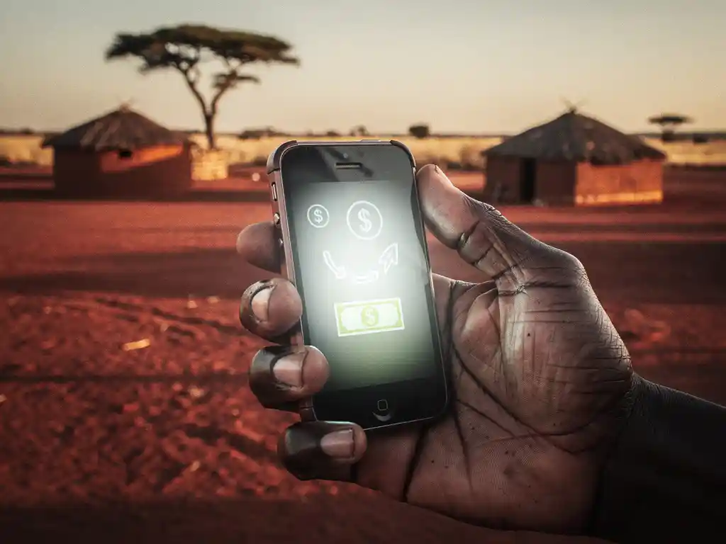 Weathered hand holding a mobile phone with a money transfer confirmation in an African savanna village at golden hour.