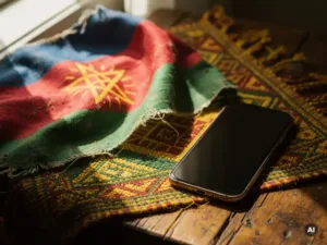Weathered Ethiopian flag draped beside a smartphone on a wooden surface with traditional woven textile, warm green, yellow, and red tones.